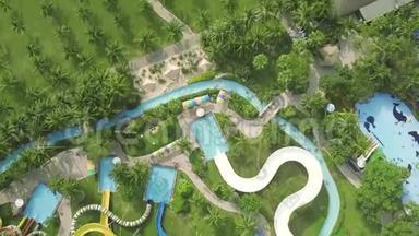 五彩缤纷的水在棕榈树景观上的游乐园中滑动。 在室外水上乐园内，可用无人机观看滑梯